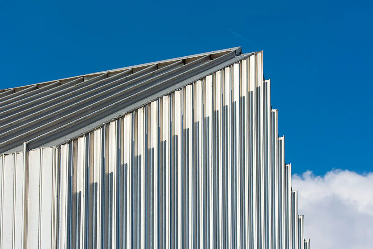 Edificação com fachada e cobertura em chapas metálicas sob céu azul